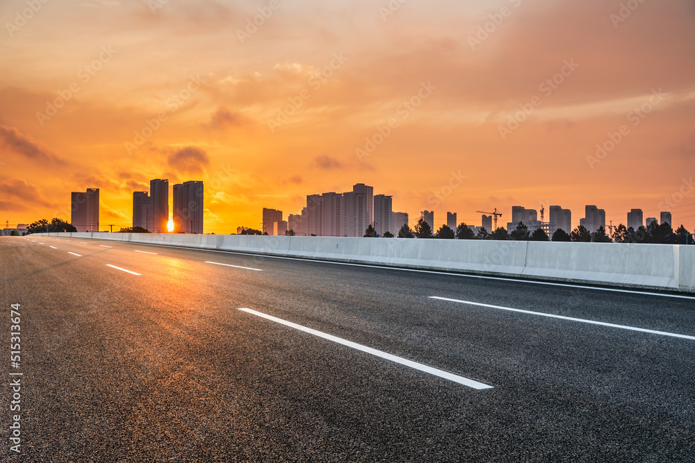 Asphalt road and modern city skyline with buildings scenery at sunset