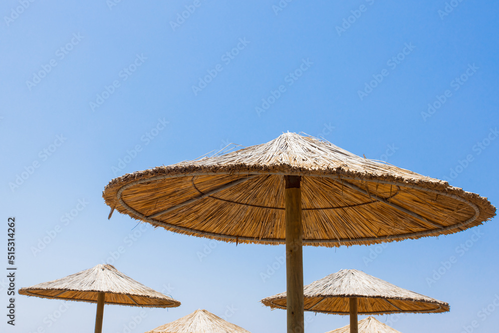 Bamboo parasols beach umbrellas with clear blue sky background on summer day