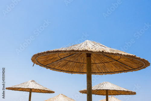 Bamboo parasols beach umbrellas with clear blue sky background on summer day