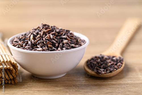 Thai purple rice seed in bowl with spoon on wooden background, Organic rice grain
