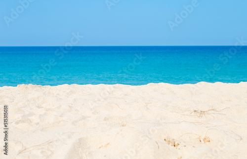 Empty white sandy beach over blurred blue sea and clear sky background, nature background, tropical summer