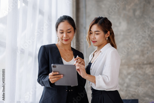 Businesswoman executive is using a tablet in meeting discussion with another businesswoman or client in modern workplace office. People corporate Asian business people team concept.