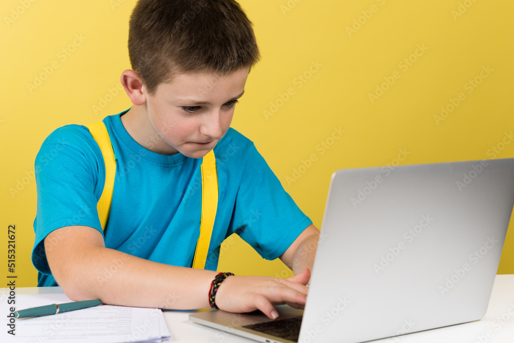 Concentrated boy typing on laptop isolated on yellow background. Concentrated boy typing on laptop isolated on yellow background.