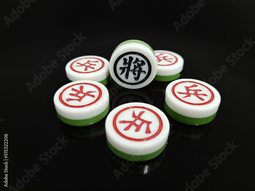 There are several Chinese chess pieces on a black background, with the black leader General and the red natural enemy