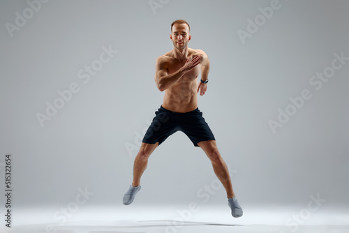 Developing endurance. Male athlete in motion isolated over gray studio background. Maintaining health and strength. Concept of sport, healthy lifestyle, motion