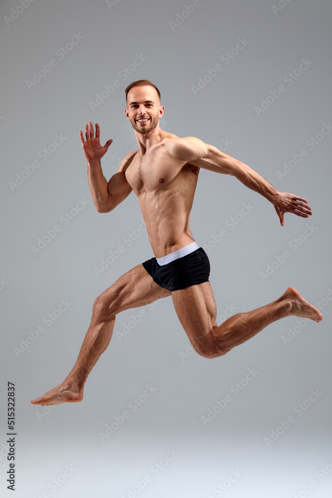 Full length portrait of a confident young sportsman shirtless jumping isolated over white background