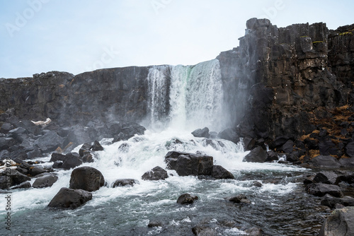 Öxarárfoss waterfall in late winter, flowing from the river Öxará over black basalt rocks into the Almannagjá gorge, Þingvellir National Park, Golden Circle Route, Iceland photo