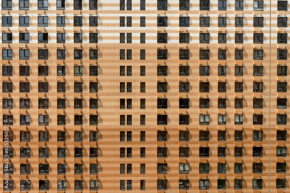 Facade of a new multi-apartment high-rise residential building with windows background. Architecture and design of a typical development of a new city district. Construction, developer, housing Facade of a new multi-apartment high-rise residential building with windows background. Architecture and design of a typical development of a new city district. Construction, developer, housing