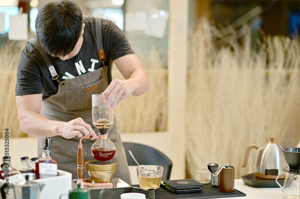Closeup of Asian Male Barista using a coffee machine in a coffee shop to make coffee for customers to order inside a coffee shop cafe in Thailand. Closeup of Asian Male Barista using a coffee machine in a coffee shop to make coffee for customers to order inside a coffee shop cafe in Thailand.