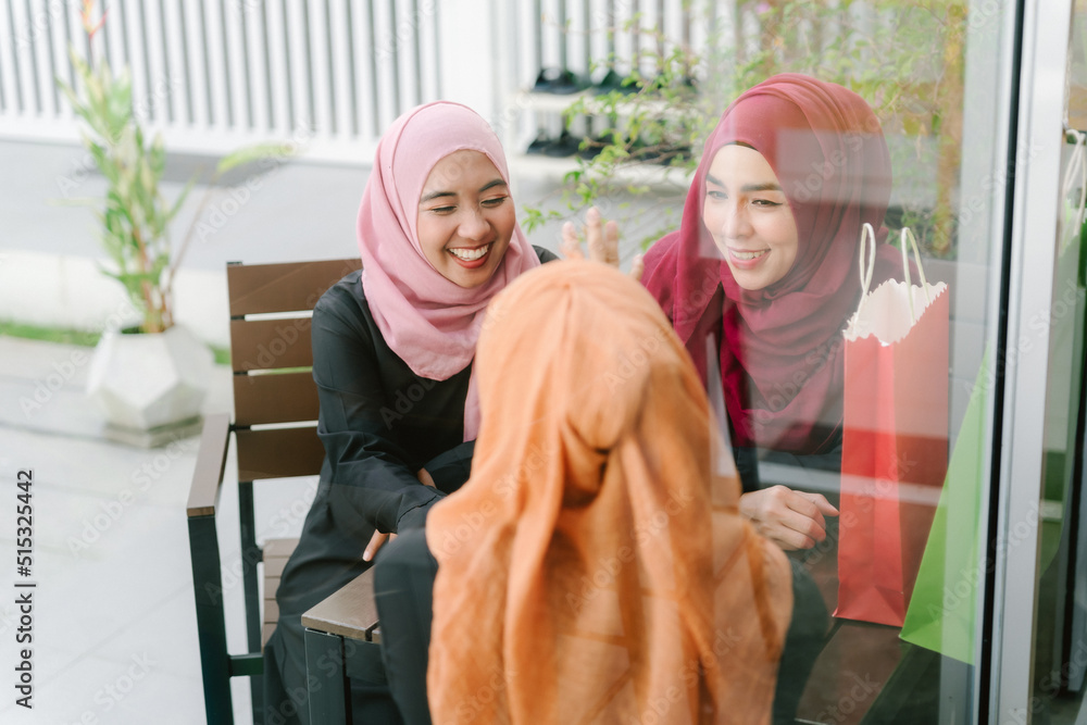 A group of Muslim Asian women sat chatting happily.