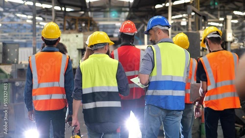 4k slow motion video, group of diversity teamwork, engineers, technician and workers team in safety uniform workwear having discussion while walking through heavy industry manufacturing factory.	