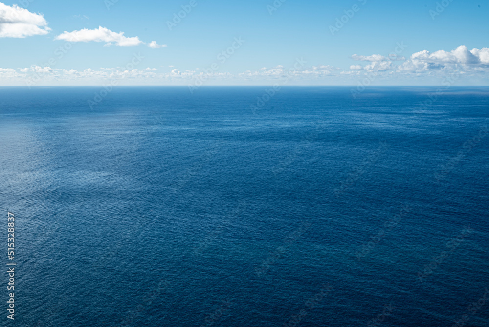 Fototapeta premium Clear and minimalistic panoramic seascape showing the endless blue waters of the Atlantic Ocean at the coast of Madeira under a sunny blue sky, also suitable as a maritime background texture