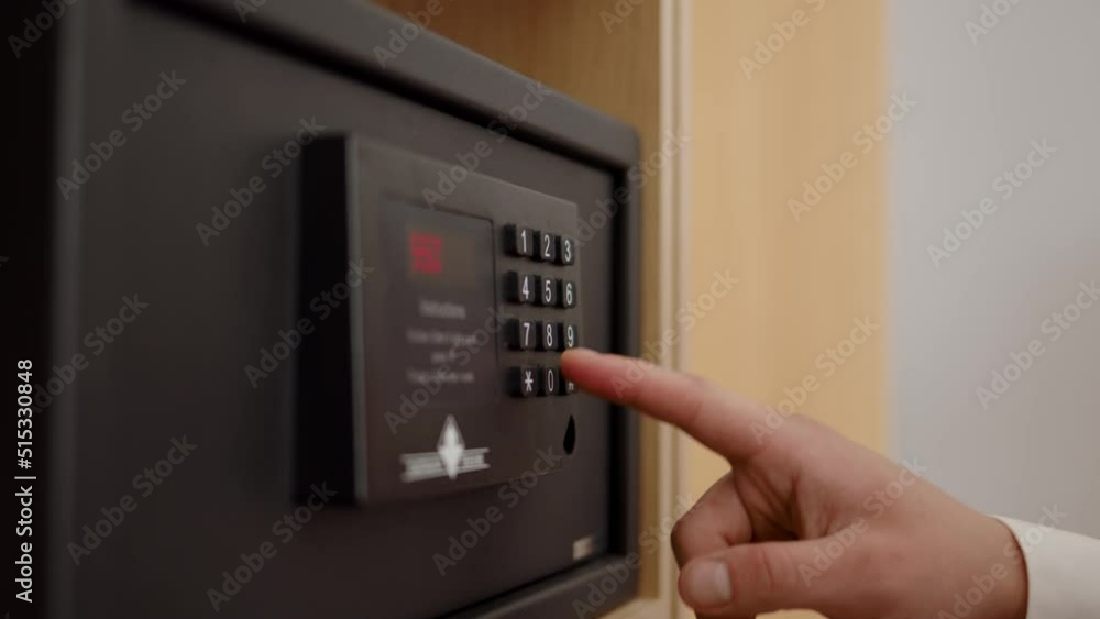 man hand in white shirt enters password on bank safe. Businessman keeps his savings and documents in strongbox, close view of entering digital code on an electronic scoreboard. man hand in white shirt enters password on bank safe. Businessman keeps his savings and documents in strongbox, close view of entering digital code on an electronic scoreboard.