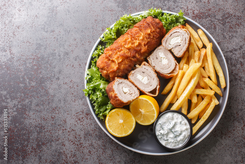 Karadjordjeva steak stuffed with kaymak, breaded and fried, served with french fries and tartar sauce close-up in a plate on the table. horizontal top view from above