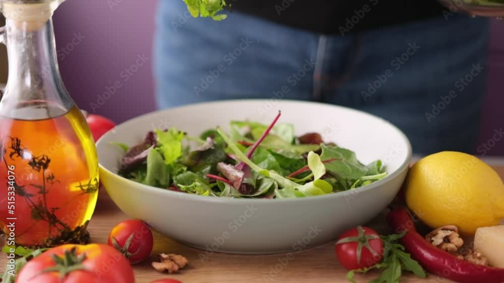 arugula salad leaves falling into ceramic bowl arugula salad leaves falling into ceramic bowl