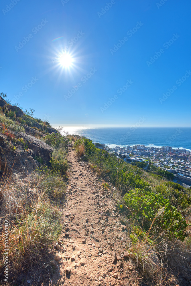 Remote mountain hiking trail on table mountain on a sunny day. Mountainous walking path high above a coastal city in South Africa against a blue horizon. Popular tourist attraction in Cape Town