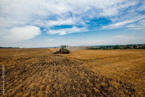 Tractor working in wheat field. Agriculture background. Harvest season