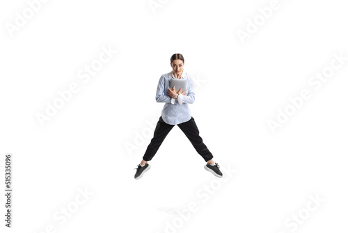 Portrait of young woman, office employee in official outfit jumping with laptop isolated over white studio background © Lustre