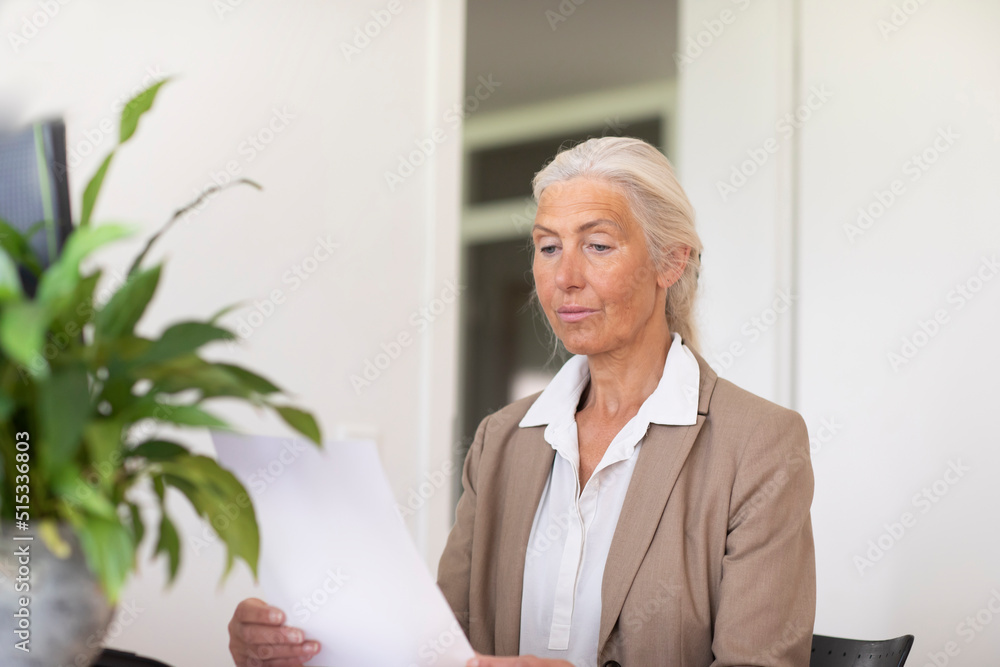 Mature businesswoman looking at document in office Mature businesswoman looking at document in office