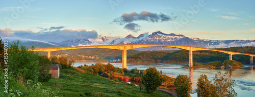 Landscape view of Saltstraumen in Nordland, Norway in winter. Scenery of infrastructure and bridge over a river and stream with snow capped mountains in the background. Traveling abroad and overseas photo