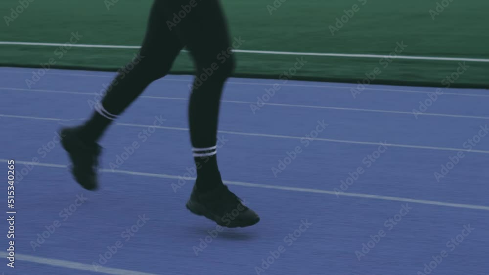 Close up female legs in black leggings and sneakers running at the stadium, jogger, jogging Close up female legs in black leggings and sneakers running at the stadium, jogger, jogging