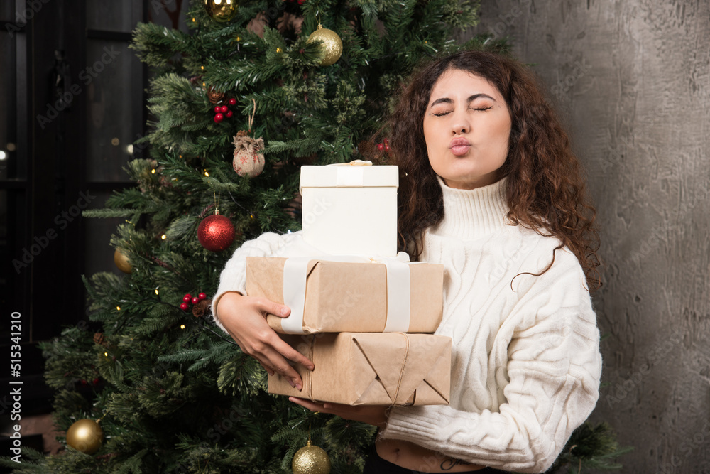 Portrait of young girl with curly hair holding a stack of gifts in a wrapper Portrait of young girl with curly hair holding a stack of gifts in a wrapper