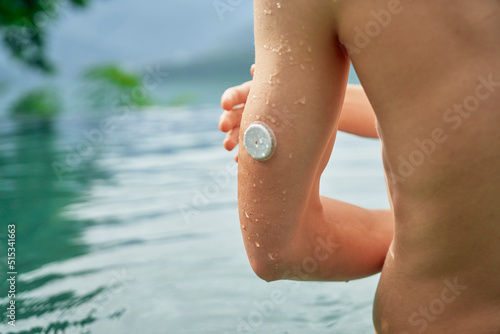 Diabetes patient in a swimmingpool with an waterproof CGM (Continuous Glucose Monitor) device to measure real-time blood sugar for a healthy lifestyle without setbacks for a good healthcare. photo