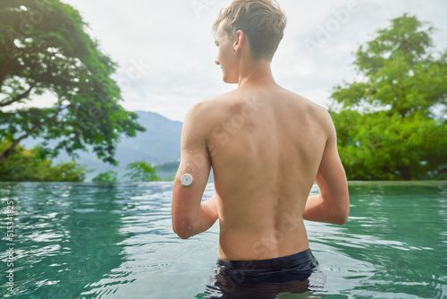 Diabetes patient in a swimmingpool with an waterproof CGM (Continuous Glucose Monitor) device to measure real-time blood sugar for a healthy lifestyle without setbacks for a good healthcare.
