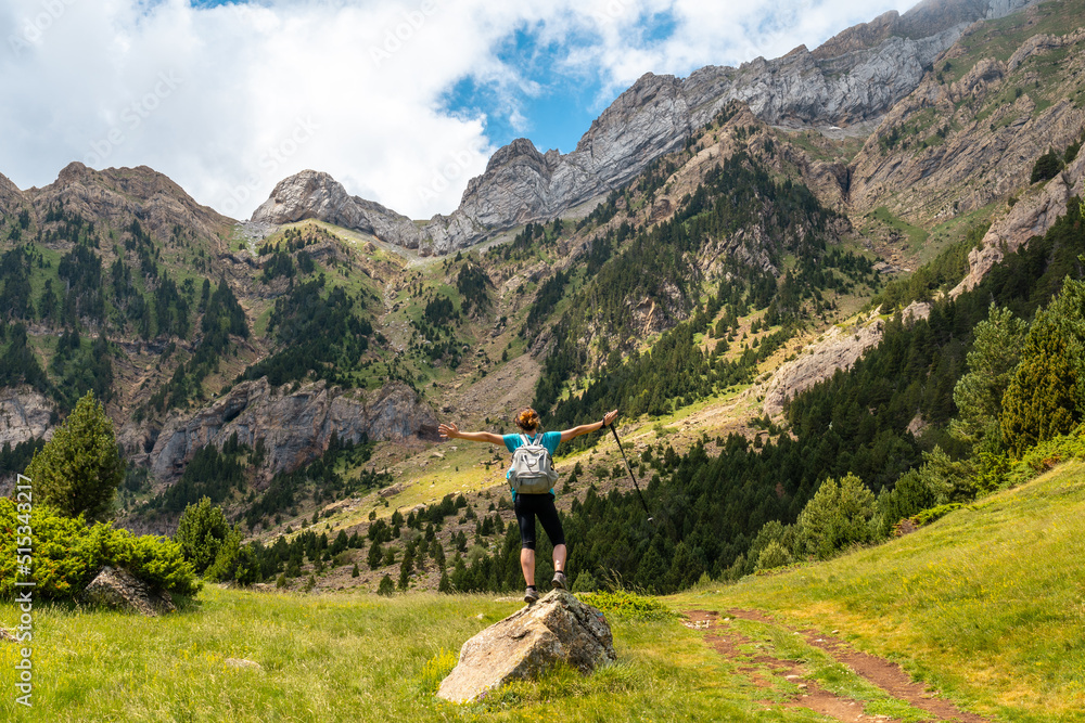 Obraz premium A young woman with open arms in the mountains in summer in the Pyrenees, Alto Gallego, Huesca, Aragon