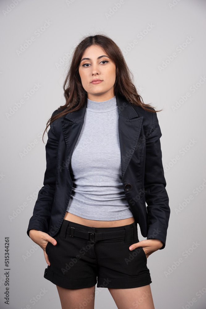 Young business woman in jacket standing and posing over a gray wall Young business woman in jacket standing and posing over a gray wall