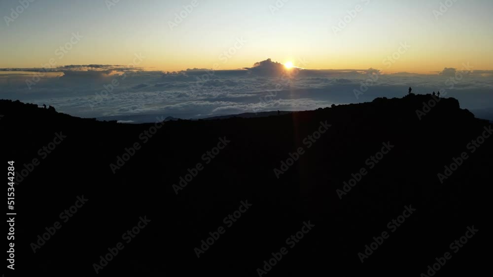 Drone footage of a man walking on a crest at the summit of the Piton