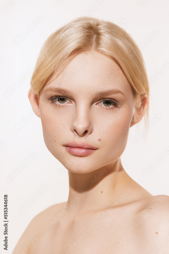 Closeup young tender girl with blond glossy hair looking at camera isolated on white studio background. Spa, cosmetics, wellbeing and skin care concept Closeup young tender girl with blond glossy hair looking at camera isolated on white studio background. Spa, cosmetics, wellbeing and skin care concept
