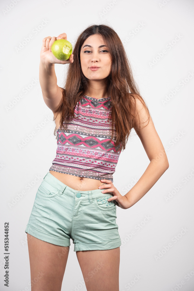 Portrait of young beautiful woman in summer clothes showing an apple Portrait of young beautiful woman in summer clothes showing an apple