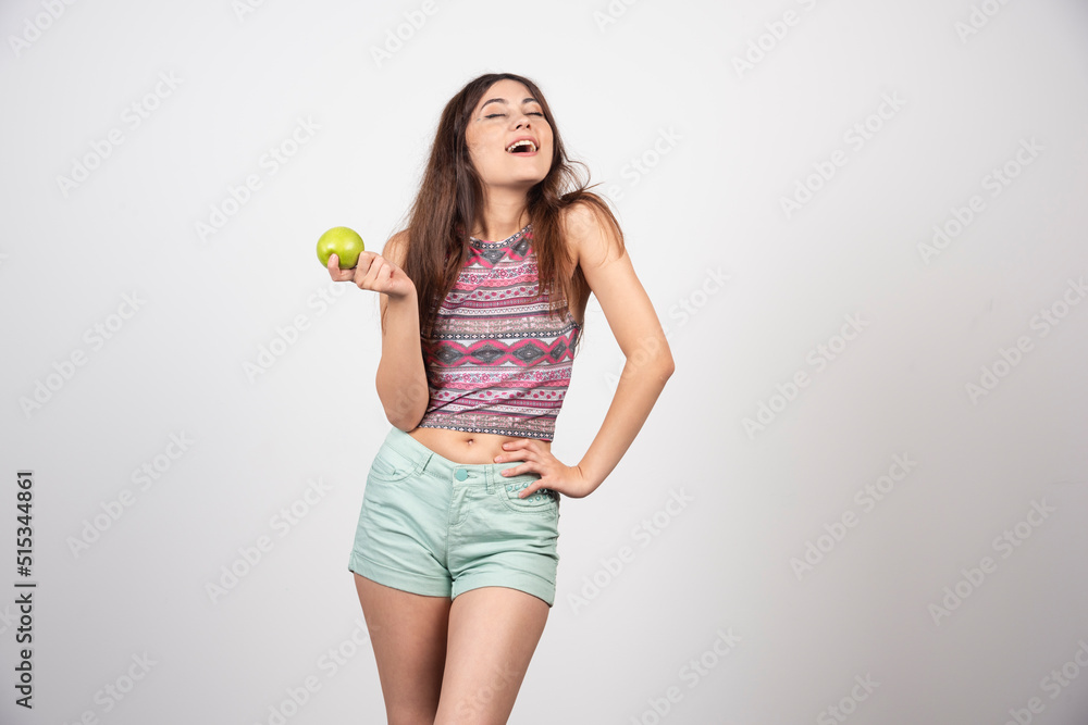 A happy woman posing with an apple in summer clothes A happy woman posing with an apple in summer clothes