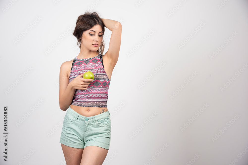 Beautiful attractive woman posing with an apple in summer clothes Beautiful attractive woman posing with an apple in summer clothes