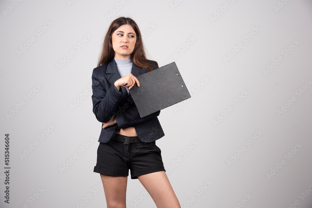 A young business woman standing with her clipboard isolated on gray background A young business woman standing with her clipboard isolated on gray background