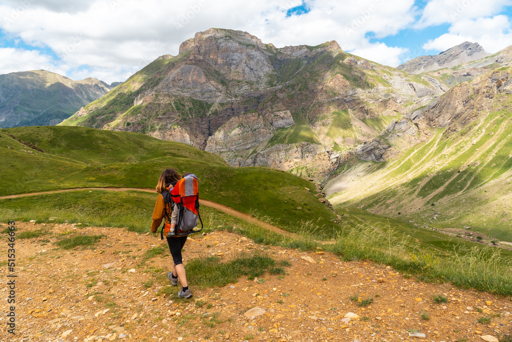 A young woman in the mountain trekking with her son in the backpack in the Ripera valley, Pyrenees
