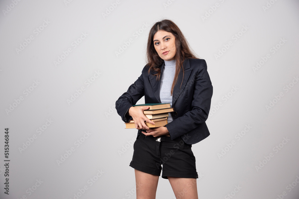 Portrait of young business woman holding a stack of books Portrait of young business woman holding a stack of books
