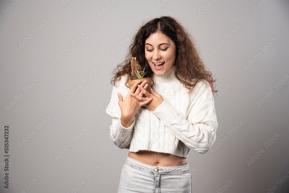 Young woman holding a plant with happy expression Young woman holding a plant with happy expression