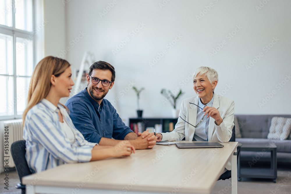 Young blonde woman talking to the female insurance agent while sitting with her husband.