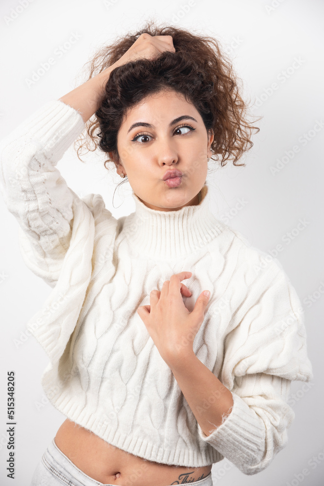 Young woman in white sweater doing funny face over a white wall Young woman in white sweater doing funny face over a white wall