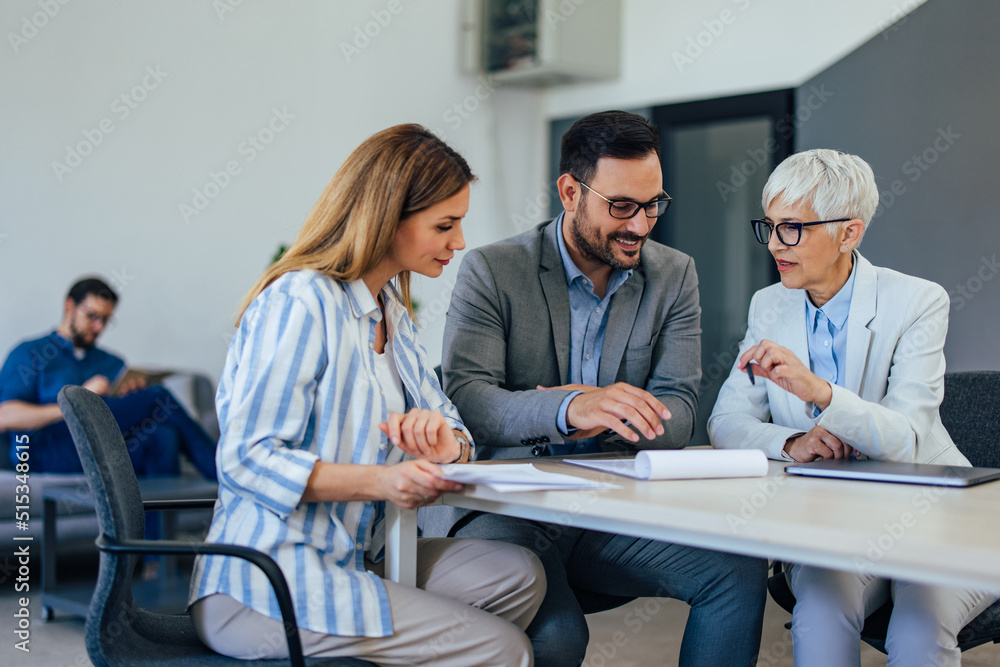 Three business colleagues working in the co-working space, a man sitting in the background. Three business colleagues working in the co-working space, a man sitting in the background.
