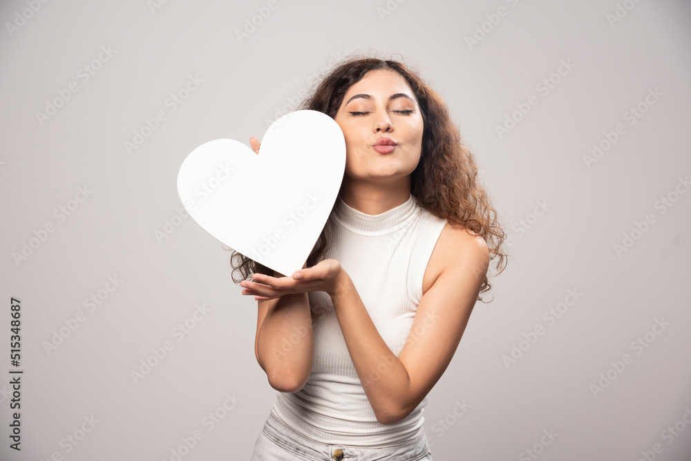 Young woman holding white handmade paper heart Young woman holding white handmade paper heart