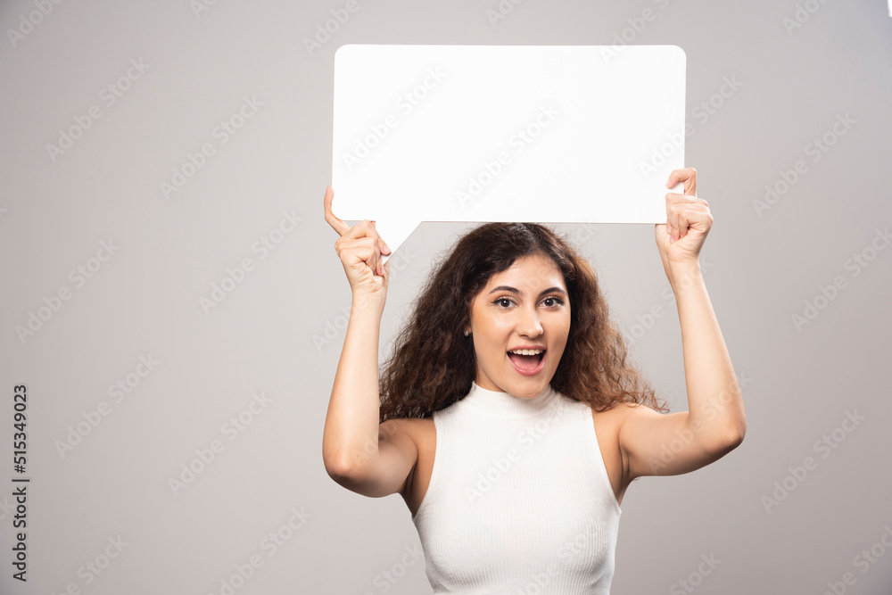 Young woman holding empty blank white speech poster overhead Young woman holding empty blank white speech poster overhead