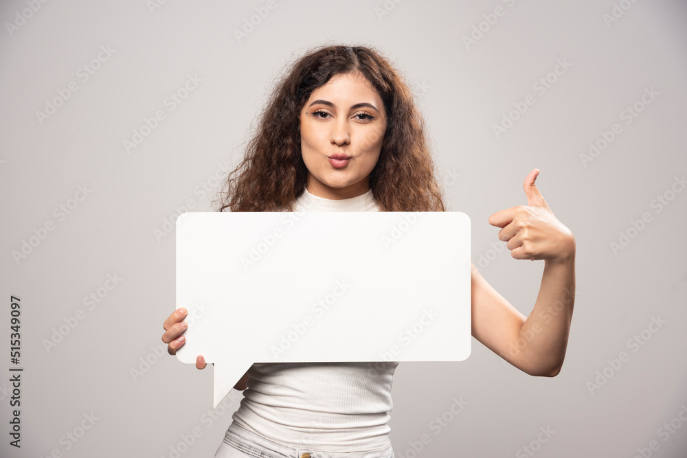 Naklejka premium Young woman holding empty blank white speech poster