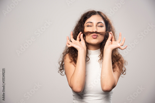 Young woman in white blouse standing over a white wall