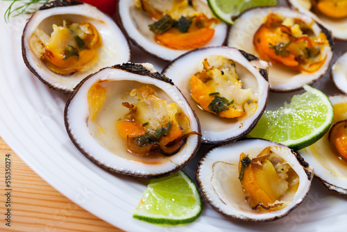 Baked Glycymeris glycymeris clams with sauce, served with lime