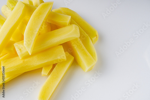 peeled potatoes sliced for french fries on a white background