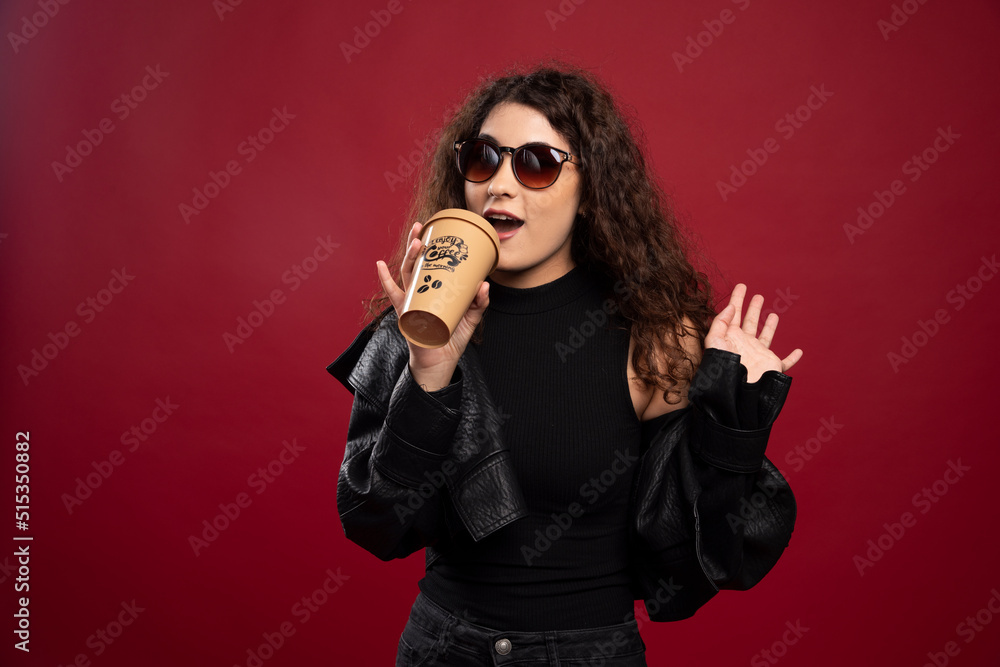 Woman in all black outfit posing with a cup and glasses Woman in all black outfit posing with a cup and glasses