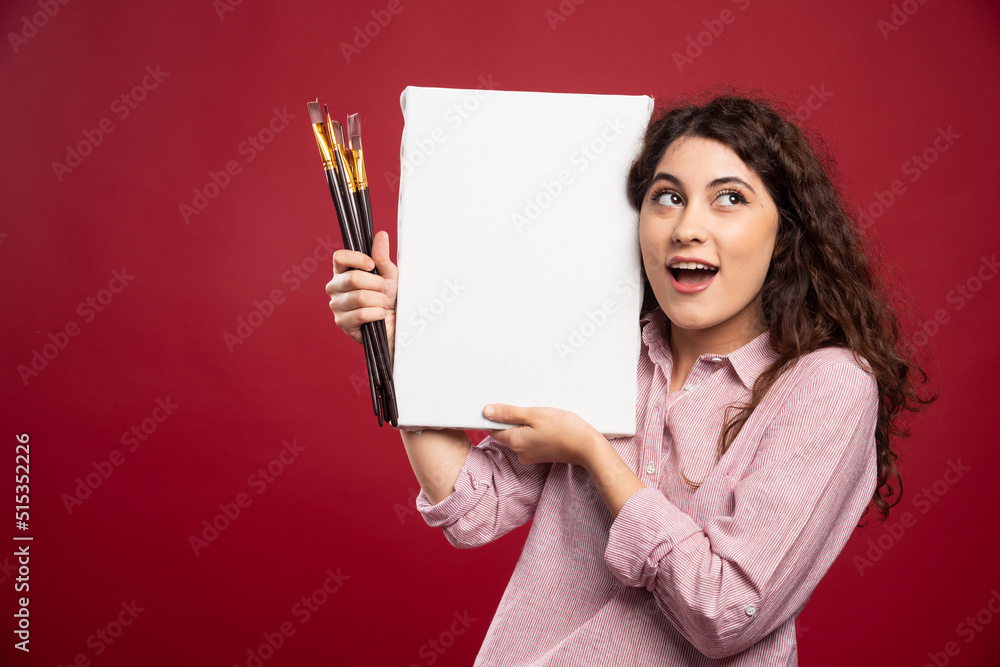 Young artist holding paintbrushes and canvas Young artist holding paintbrushes and canvas